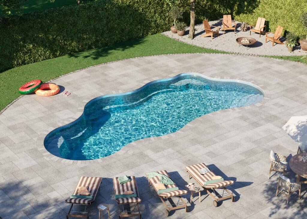 Fiberglass pool with a unique shape surrounded by patio furniture and inflatable pool toys, emphasizing outdoor relaxation and family-friendly design options in a landscaped yard.