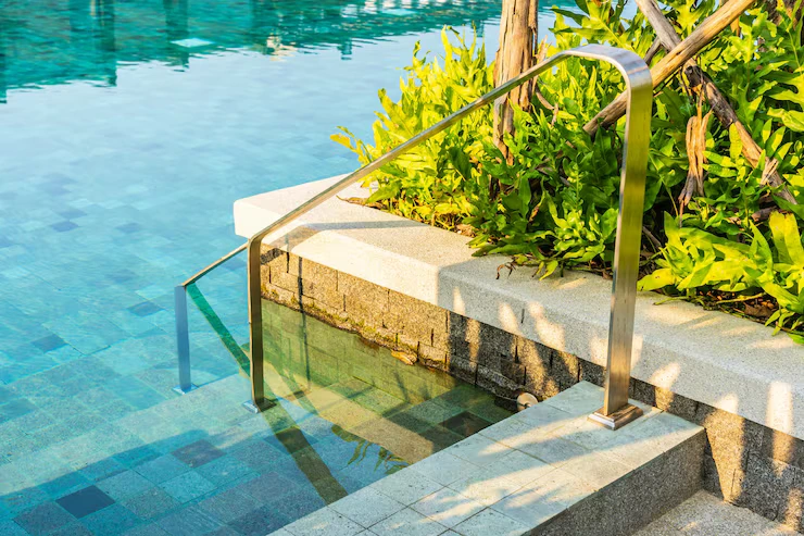 Outdoor swimming pool with stair ladder and surrounding greenery, emphasizing accessible design for relaxation and leisure.