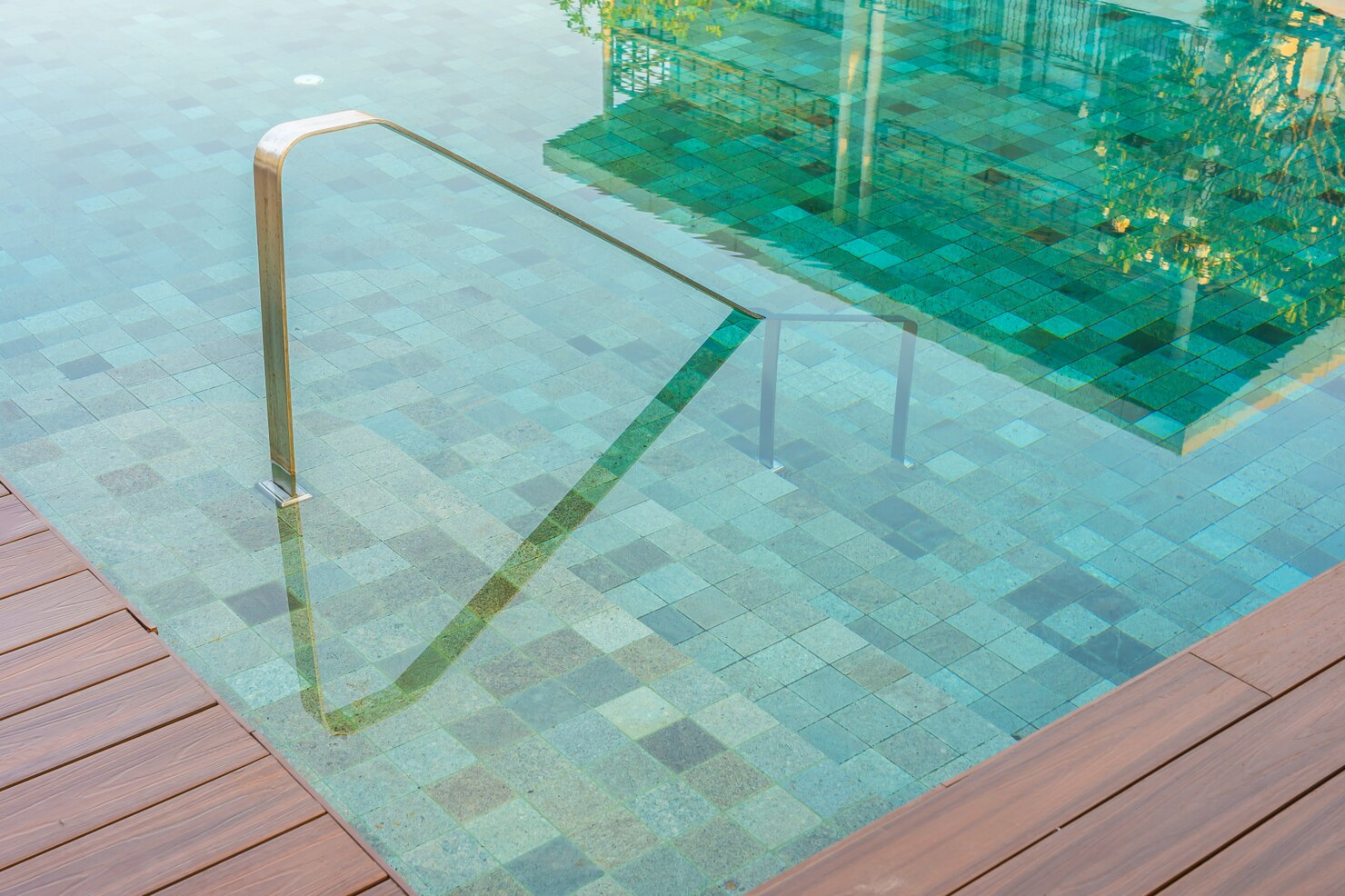 Outdoor fiberglass swimming pool with stair ladder, featuring a smooth surface and clear water, surrounded by tiled flooring, emphasizing low maintenance and durability.